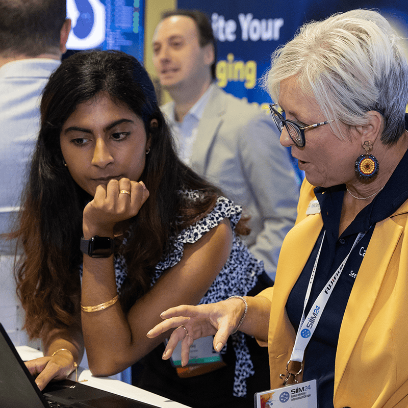 People looking at a laptop at a conference
